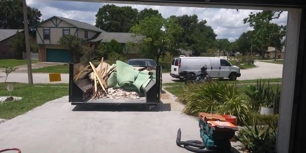 12 yard dumpster rental front driveway loaded with construction debris such as carpet padding tile