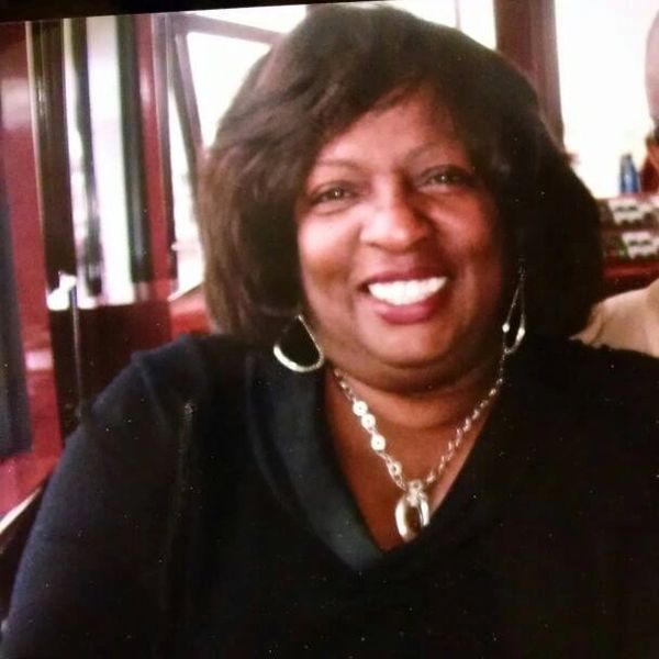 Smiling woman with dark hair in a cozy setting.