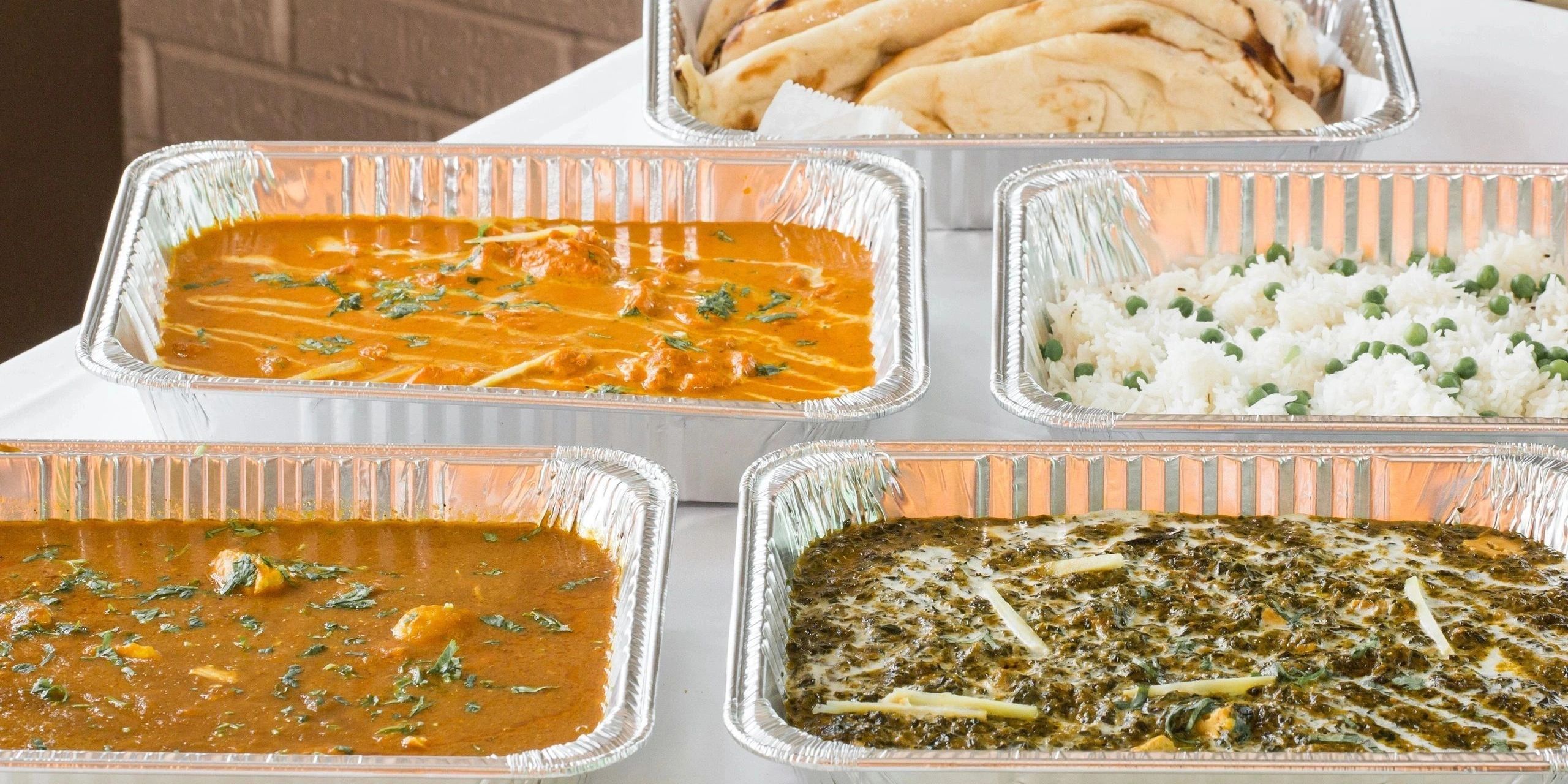 Indian meals in foil containers with naan, rice, and curries.