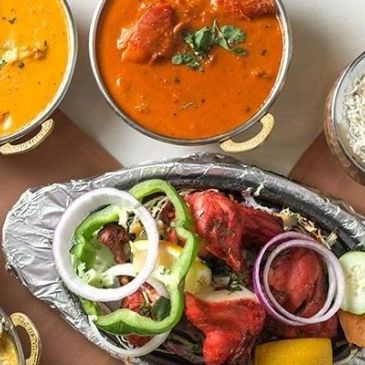 Indian meal with curry, rice, and tandoori chicken.