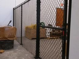 Black vinyl chain link fence with a chain link gate. Posts are welded to base plates and anchored.