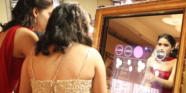 girls taking pictures in the mirror photobooth photo strips prom