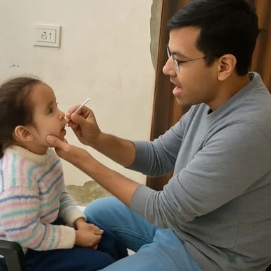 Man using a swab to test a young girl's mouth indoors.