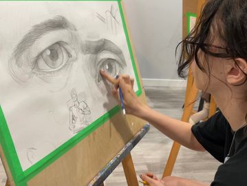 Person sketching a large eye on paper.
