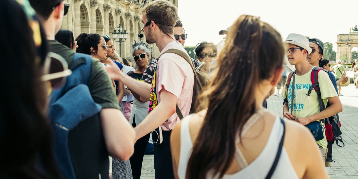 A tour guide leads a group of tourists in a historic city square.