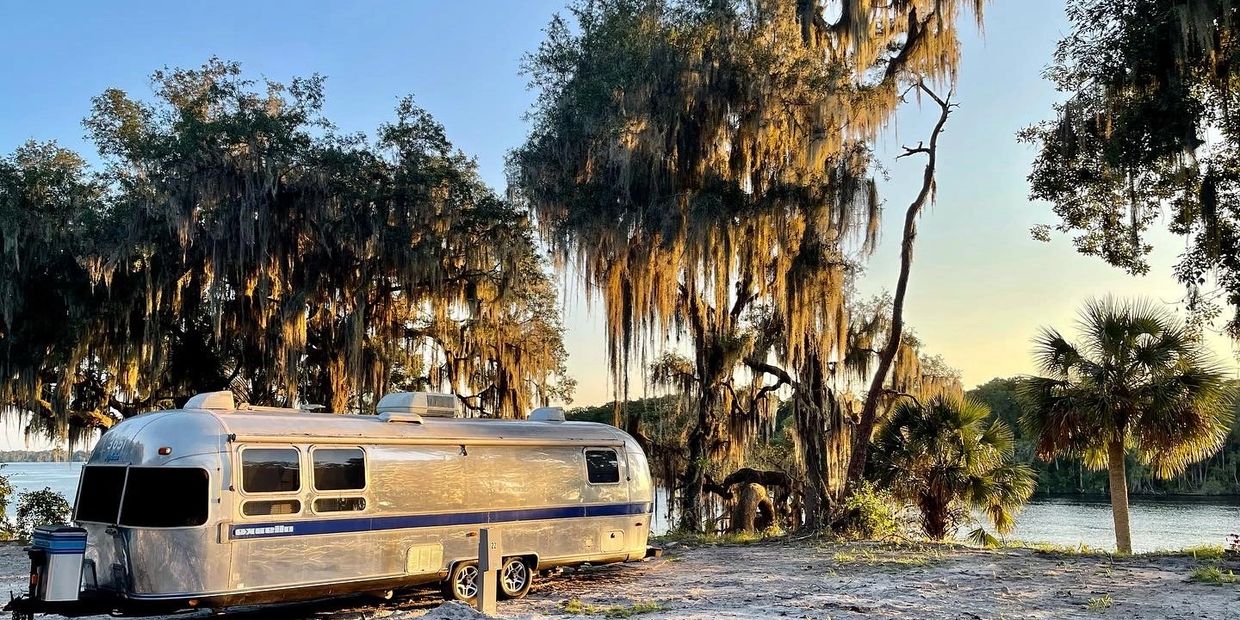 An Airstream RV overlooking a river.