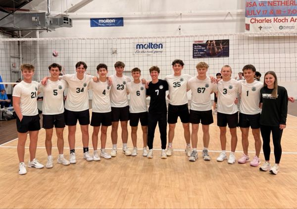 High school boys volleyball team posing on court after a match.