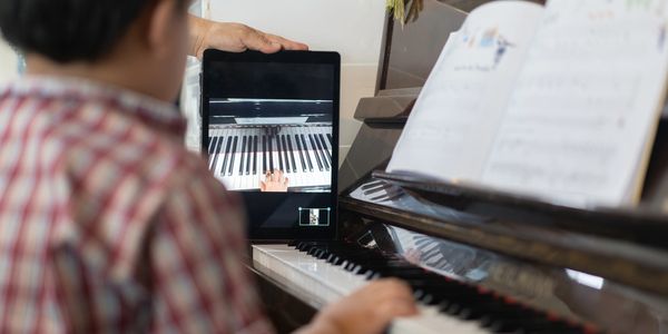 Young boy watches piano keyboard on tablet screen during hybrid and online music lessons in St Louis