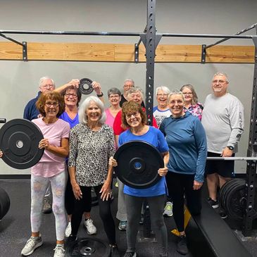 Group of members holding barbell plates at the gym