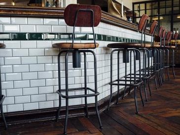 Bar seating with white subway tile and dark stools.