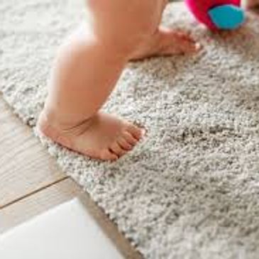 Baby feet standing on a shag rug.