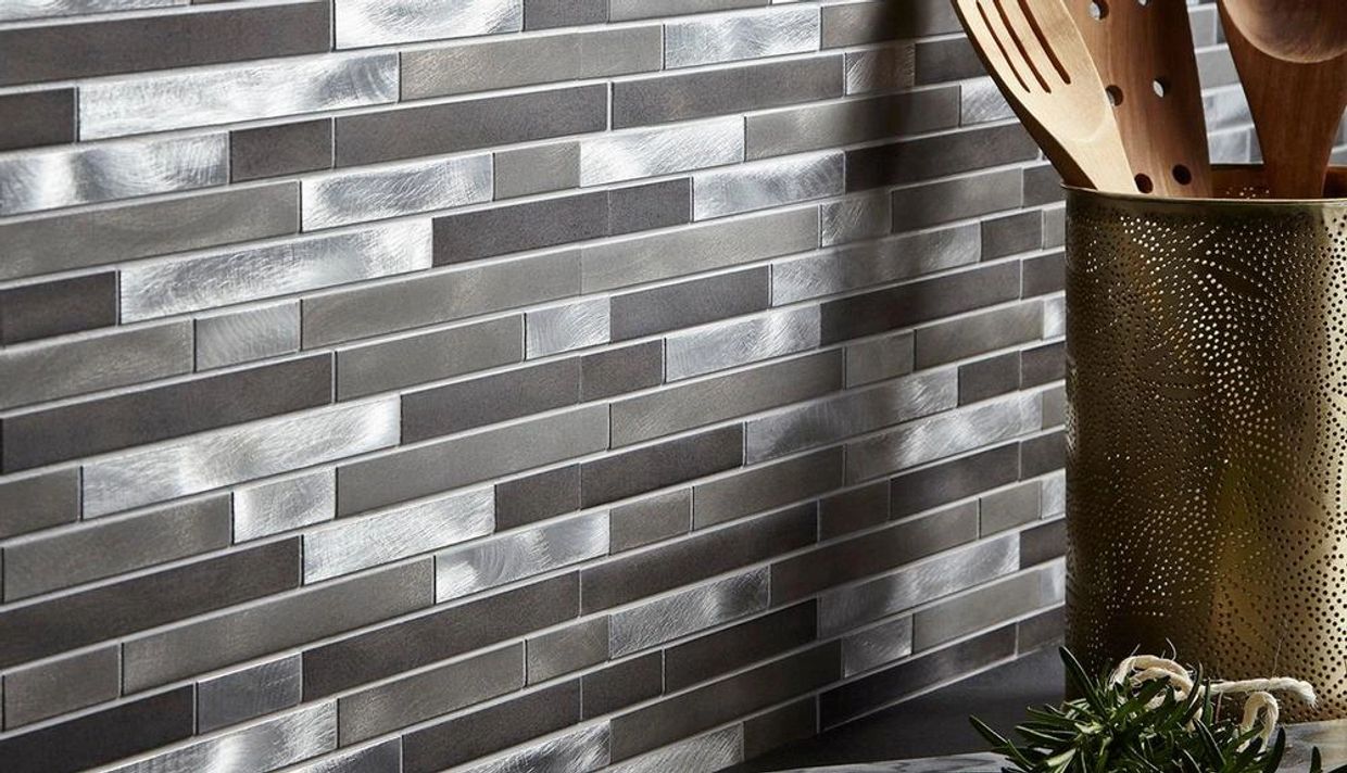 Close-up of a kitchen backsplash with metallic silver and gray rectangular mosaic tiles.