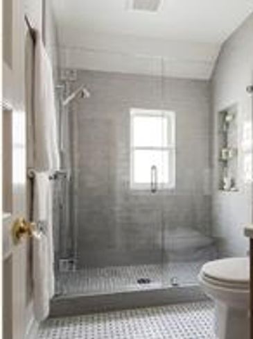 Walk-in shower with glass door and gray tile.