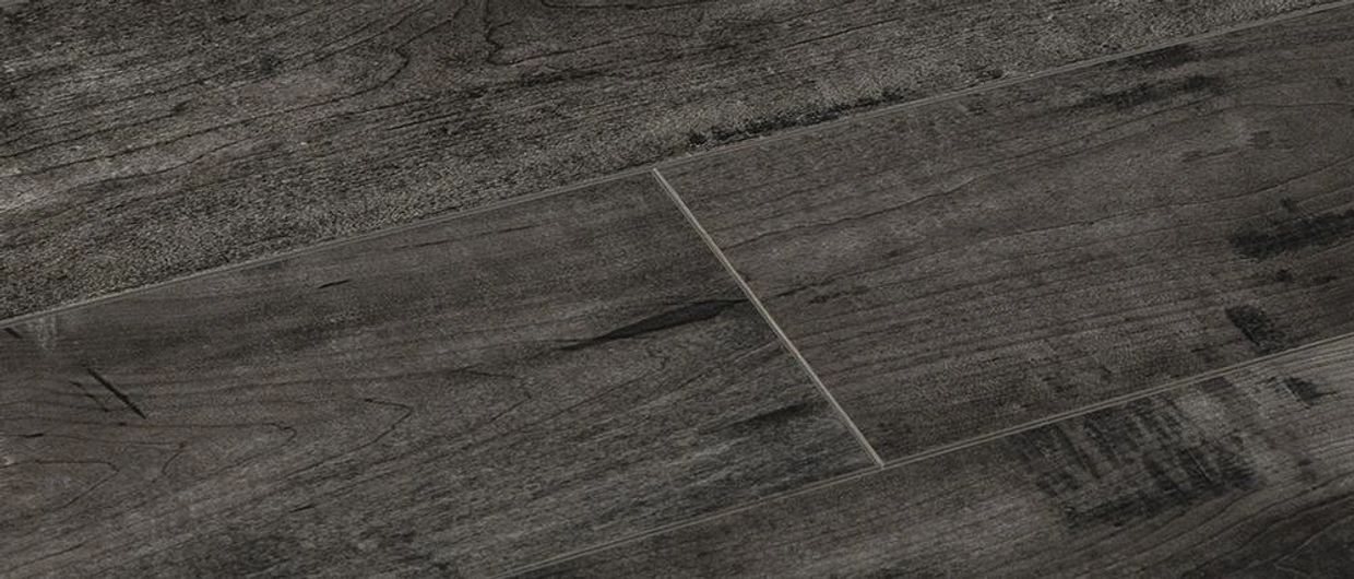 Close-up of dark gray, distressed wood-look flooring planks with visible grain.