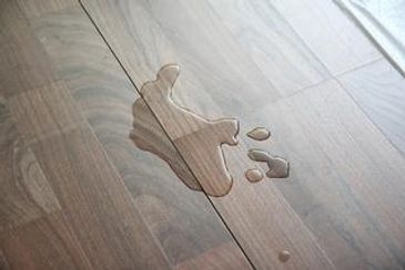 Close-up of laminate flooring with spilled water.