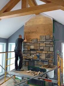 Fabrication d'un foyer en pierre décorative  à l'intérieur d'un chalet alpin.