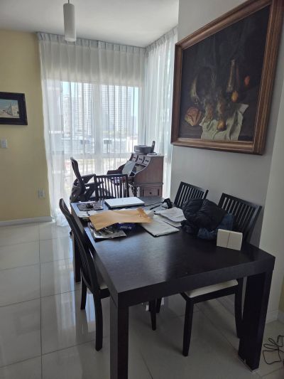 Bright dining room with dark furniture and large paintings on the walls.