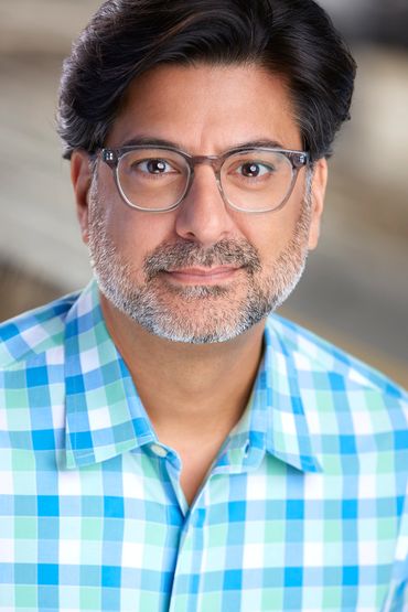 Man with glasses smiling in a checkered shirt.