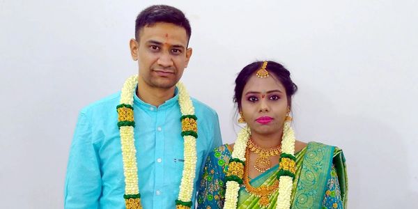 Newlywed couple in traditional Indian attire with flower garlands.