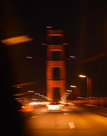 Capturing the feeling of a high energy night driving across the Golden Gate Bridge with car lights o