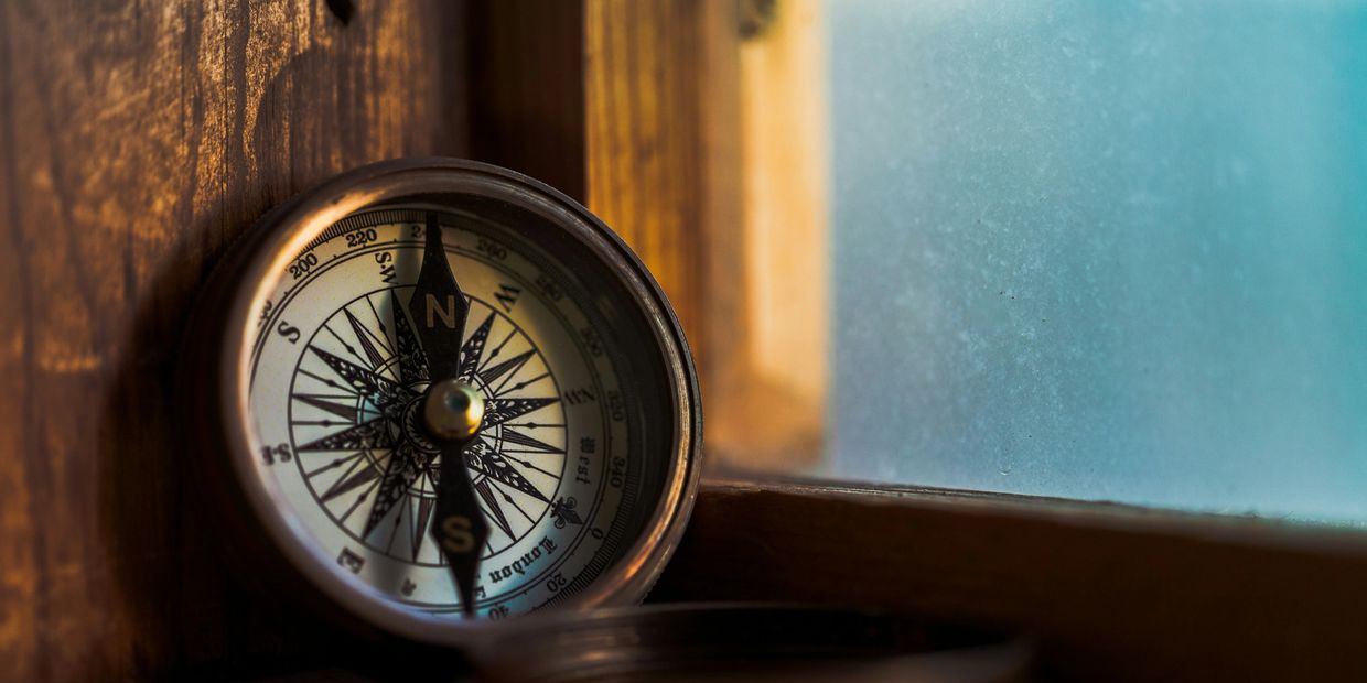A compass placed near a window with soft light.