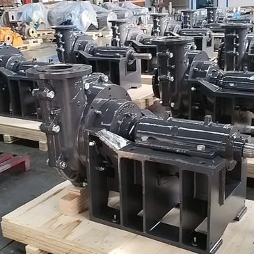 Industrial pumps arranged on wooden pallets in a factory setting.