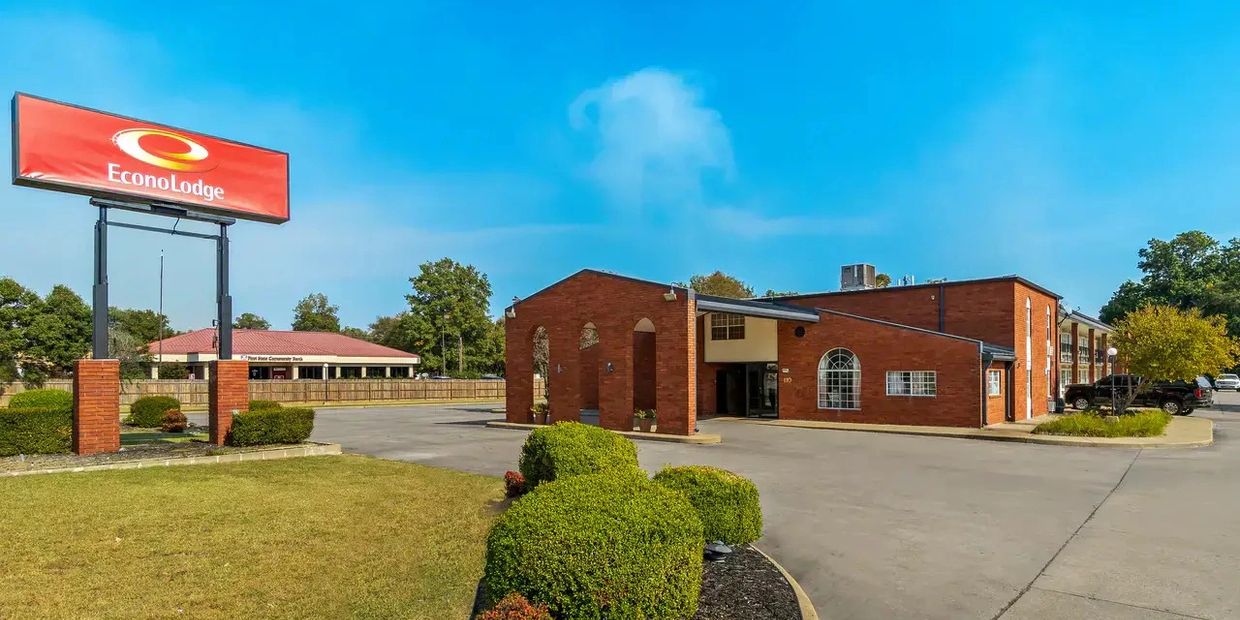 Econo Lodge motel with brick exterior and clear blue sky.