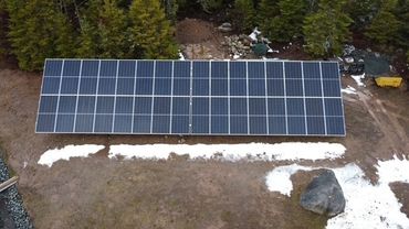 A large solar panel array installed on a cleared forest ground area.