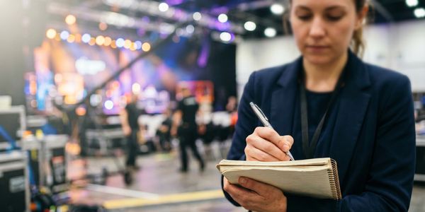 Woman writing notes at a busy event venue.