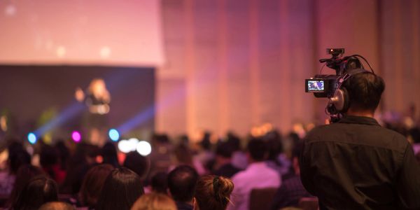 Cameraman filming speaker at a conference.