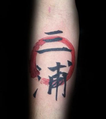 Forearm tattoo of black Japanese kanji characters with a red brushstroke circle.