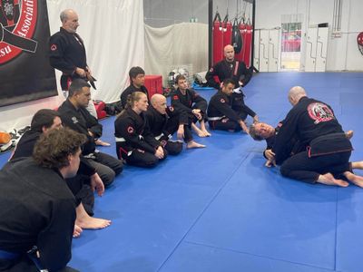A martial arts instructor demonstrates a technique to attentive students in a dojo.
