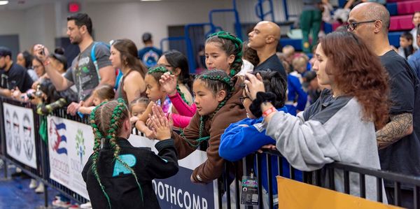 Children and adults exchanging high-fives and taking photos at an indoor event.
