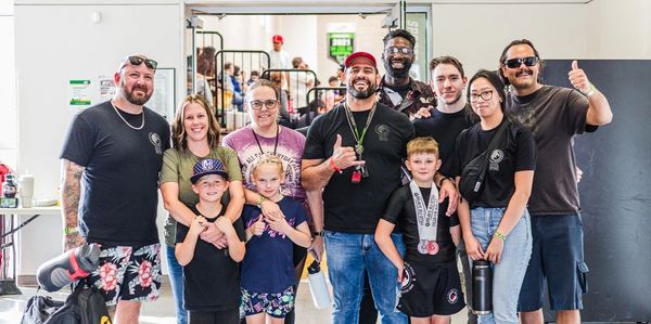 Group of smiling people posing indoors, including children and adults.