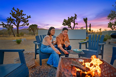 Guests roasting marshmallows around a fire pit at a Joshua Tree Airbnb at sunset