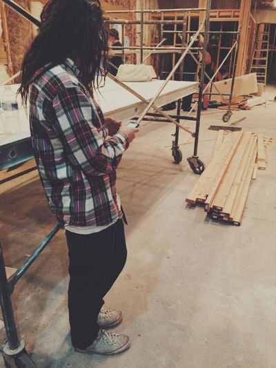 Person in plaid shirt using phone at a construction site.