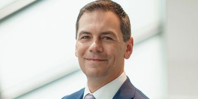 Confident man in a blue suit smiling gently at the camera.