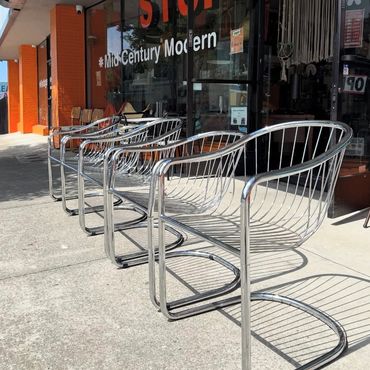Row of shiny metal chairs outside a mid-century modern store.