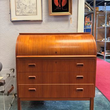 Mid-century wooden roll-top desk with three drawers in an antique store.