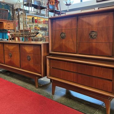 Mid-century wooden dressers with decorative handles in a vintage shop.