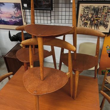 Stacked wooden chairs with curved backrests in an art-filled room.