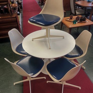 Mid-century modern table with five matching chairs, one placed on top.