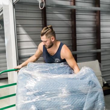 A mover moving a heavy item on a moving dolly in a public storage