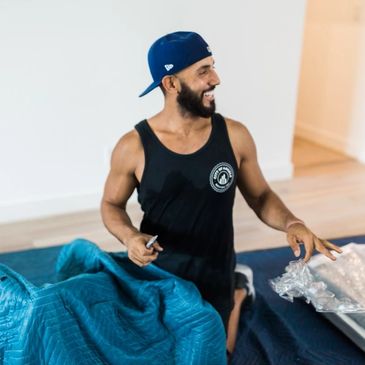 A mover smiling while he is unwrapping furniture