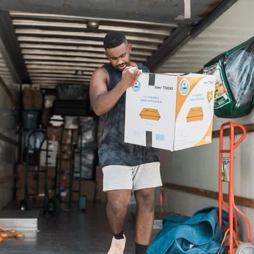 A mover carrying a box while getting out of the moving truck