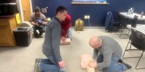 two men performing proper CPR on a training doll - Focal Pointe LLC