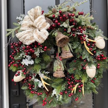 Festive Christmas wreath with red berries, pine cones, and a large bow.