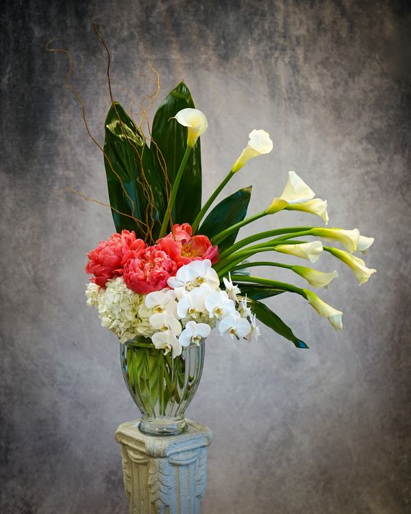 A beautiful tall floral arrangement with Calla lilies, peonies, orchids, white hydrangeas.