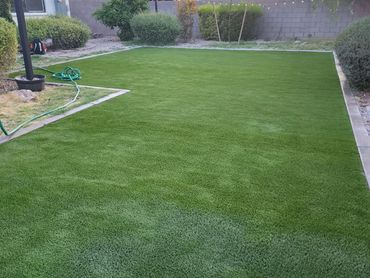 Twilight over a lush backyard with an artificial grass installation by Tempe Turf Installers.