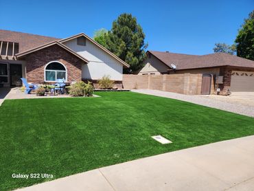 A home on a sunny day with a dark green artificial turf installation by Tempe Turf Installers,